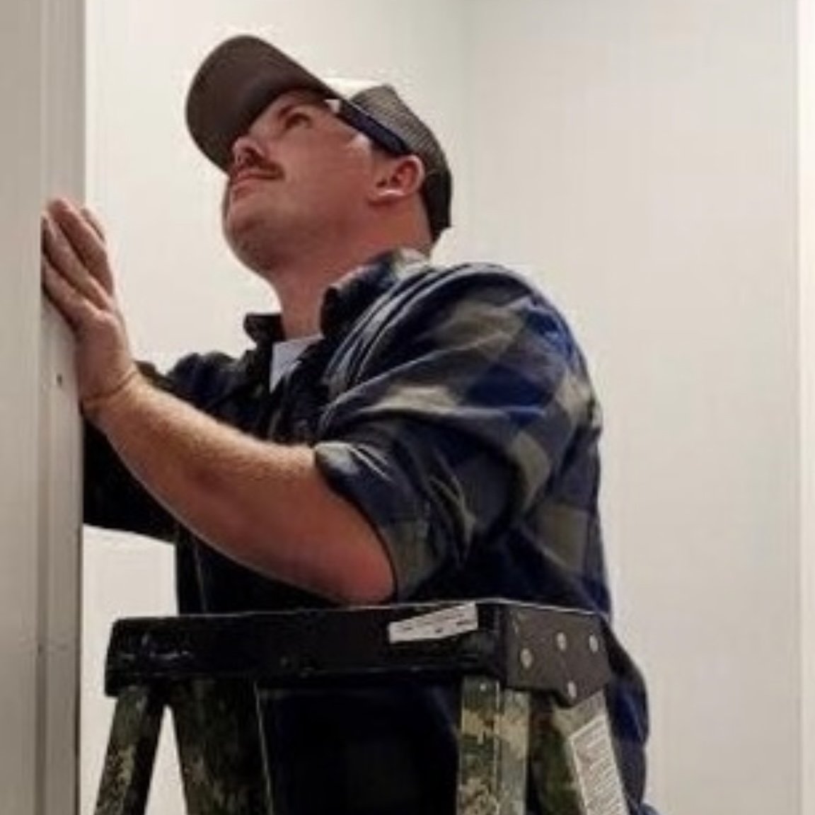 Jeremy Hatley owner of Hatley Construction on a ladder doing finish work