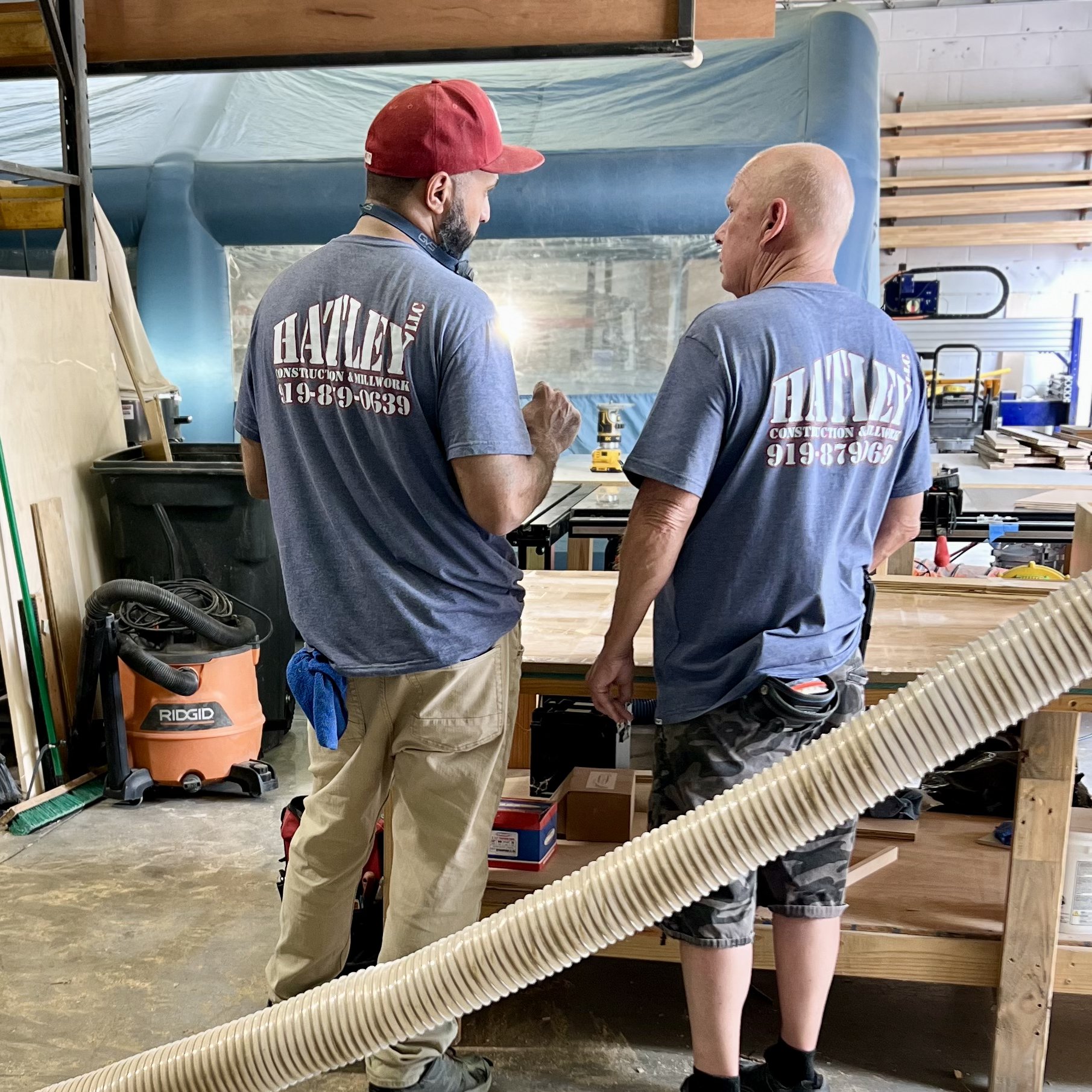 Paul and Miguel in the Hatley Construction shop wearing branded shirts