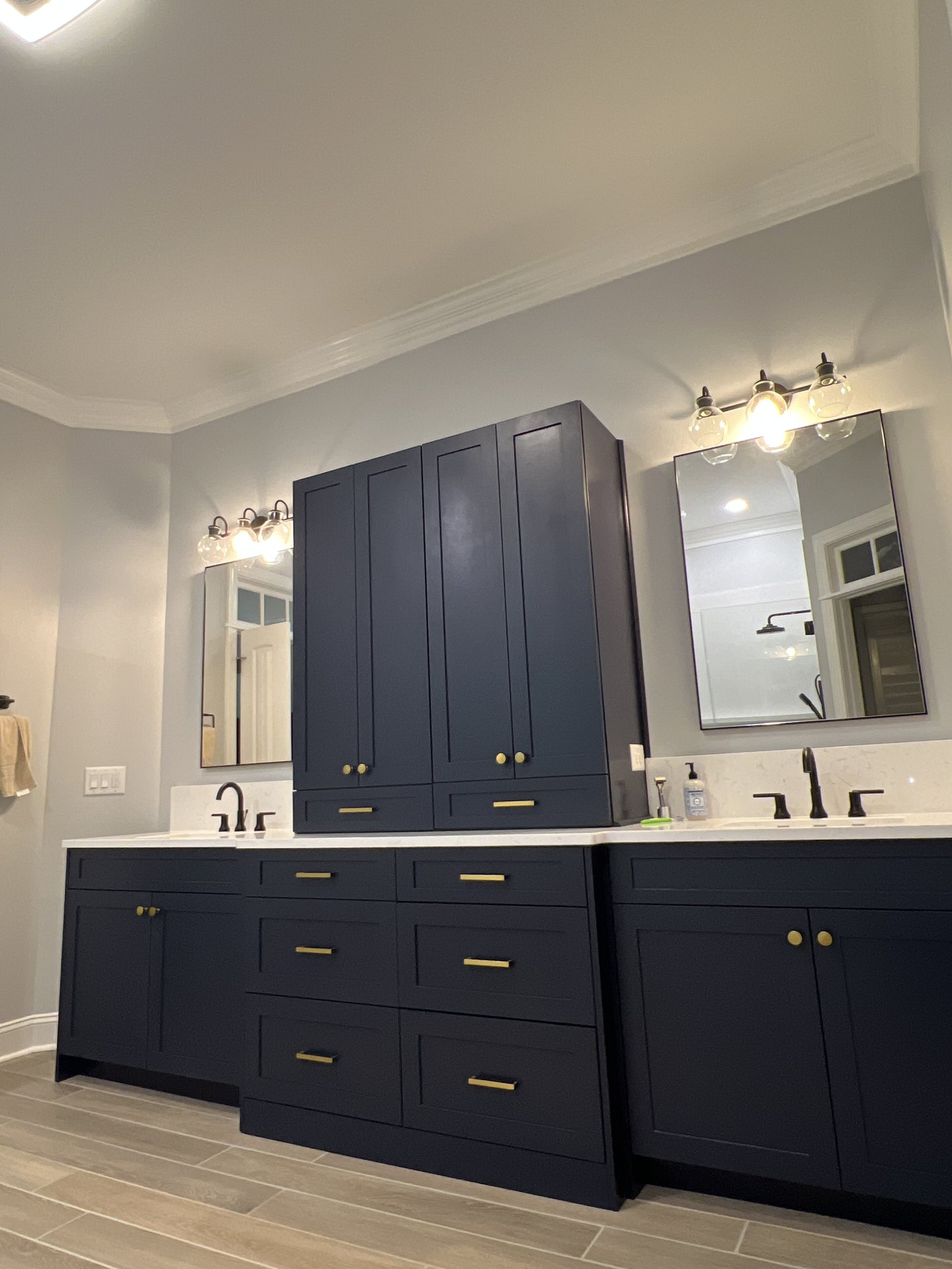 Navy blue double vanity with gold hardware and linen tower