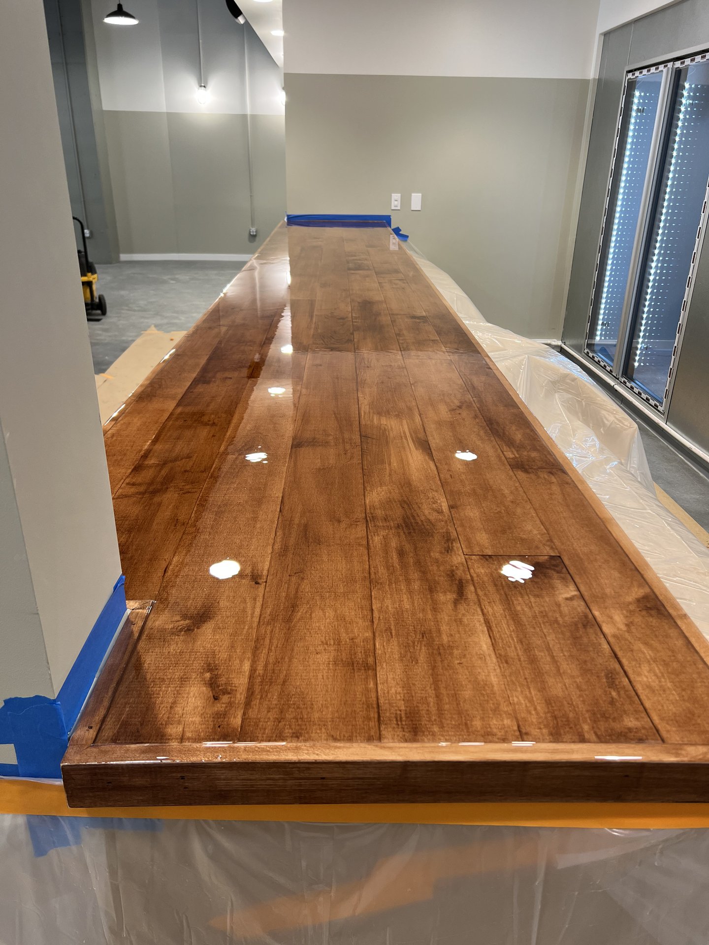 Stained hardwood bar top being finished with epoxy coat